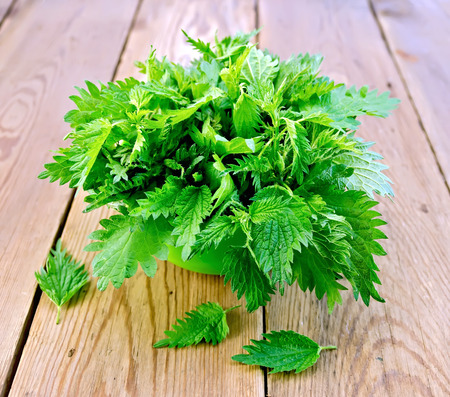 Fresh green nettle in a bowl on a wooden boards backgroundの写真素材