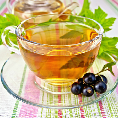 Tea with blackcurrants in cup on tableclothの写真素材