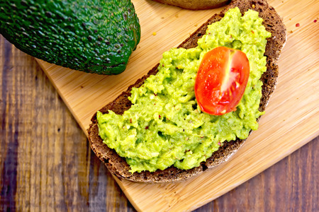 Sandwich with guacamole avocado and tomato on boardの写真素材