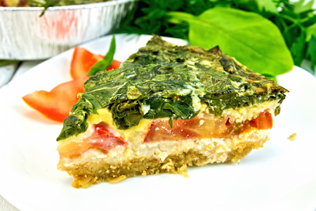 Celtic cake with spinach, tomatoes, oatmeal and eggs in a white plate in a baking dish from a foil...
