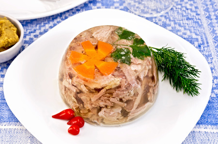 Jellied pork and beef with carrots and parsley on a plate with a sharp pertsemey and dill, mustard...