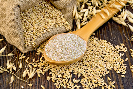 Bran flakes oat in spoon, a bag of grain oats, oat ears on the background of wooden boardsの写真素材