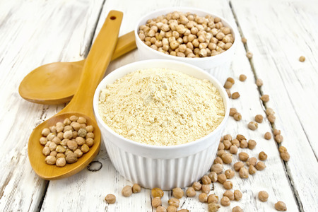 Flour chickpeas and chick-pea in white bowls and spoon on a background of wooden boardsの写真素材