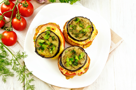 Toasted with egg, tomato, cheese and eggplant slices of bread, sprinkled with dill and parsley in a dish on napkin on the background of wooden countertop topの写真素材