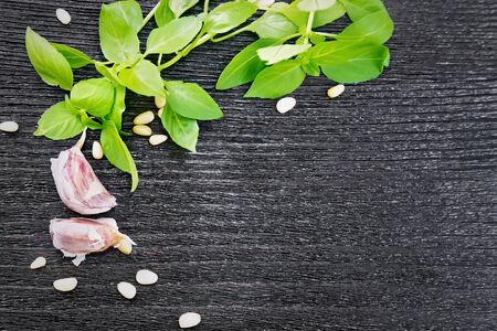 Frame of ingredients for pesto sauce: garlic, pine nuts and basil on a black wooden board backgroundの写真素材