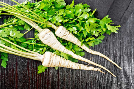 Whole parsley roots with green tops, a napkin on wooden board background from aboveの写真素材