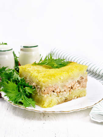 Mashed potato casserole with salmon fillet and lettuce in a plate, napkin, garlic on the background...