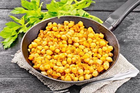 Chickpeas stewed with celery, tomatoes, onions, carrots and garlic in a pan on sackcloth on a wooden board backgroundの写真素材