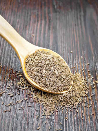 Cumin seeds in a spoon on a wooden board backgroundの写真素材