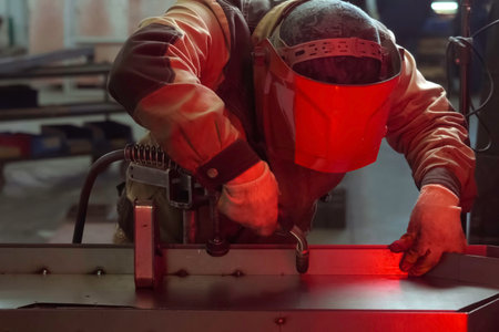 A welder in a mask welds stainless steel parts.