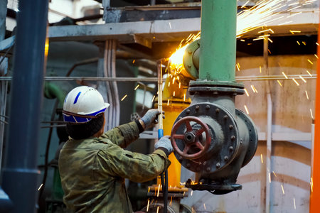 A welder welds a pipeline. Installation of pipelines at an oil refinery.