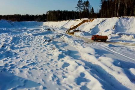 An orange dump truck in winter in a snow covered sand quarry.の写真素材