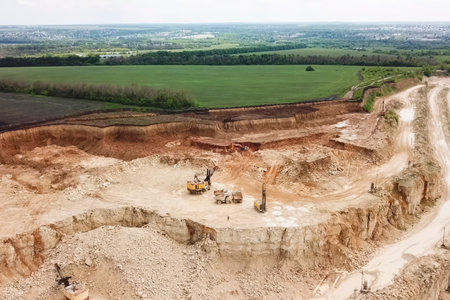 Excavators and dump trucks and other equipment in the sand