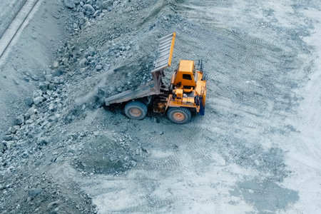 A dump truck pours out crushed stone near the railway
