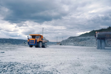 A larger mining dump truck in the quarry against background of rocks.