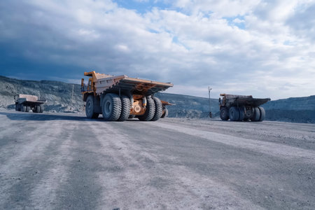 A larger mining dump truck in the quarry against background of rocks.