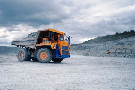 A larger mining dump truck in the quarry against background of rocks.