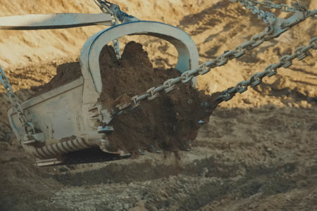 A dragliner bucket on cables scoops up soil at a gold mine