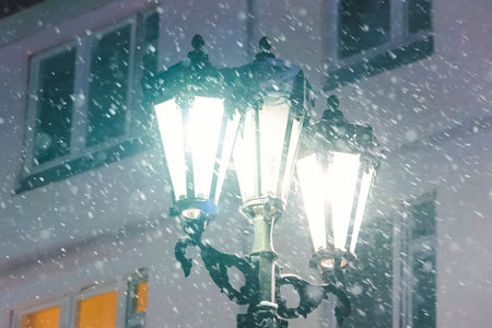 Three lampshades of a street lamp against the background of the building in winter it snows.の写真素材