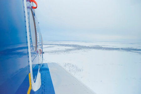 View from the helicopter on the snow-covered tundra. A helicopter is partially visible