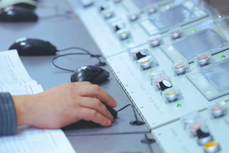 the operator's hand holds a computer mouse at the control panel of the plant's LNG equipment.