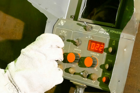 Worker's hand in a glove on the control panel of LNG equipment.