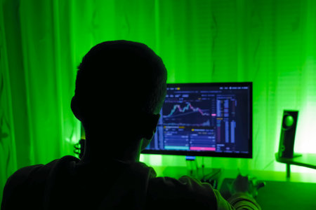 Rear view of man broker at monitor tracking stock charts.の写真素材