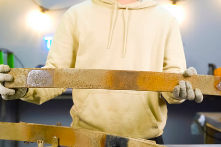 Old rusty truck springs in the hands of a man wearing gloves.