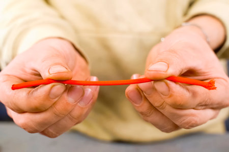 A man holding a red shoelace in his hands.の写真素材