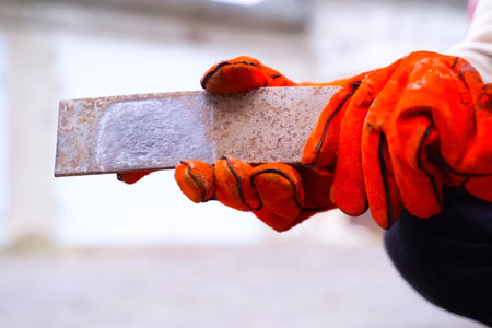 Worker in red gloves of welder holding steel billetの写真素材
