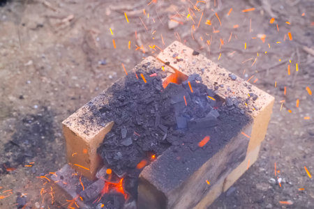 Campfire lit between fireproof bricks for heating metal.