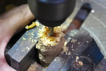 Drilling in a wooden hemp clamped in a vice. A drill bit on wood drills wood