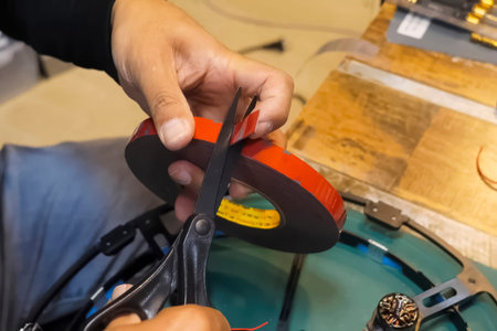 cutting a piece of double-sided tape from the roll with scissors.の写真素材