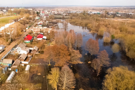 The river, overflowing its banks, floods the gardens and houses of the village, local flooding.の写真素材