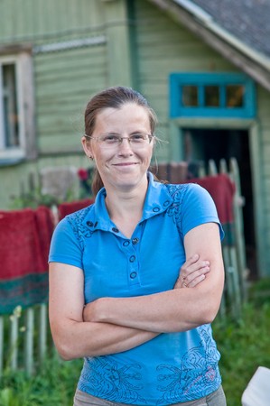 The woman wearing spectacles costs against the rural houseの写真素材