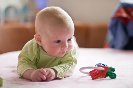 The baby lies on a tummy with a toyの写真素材