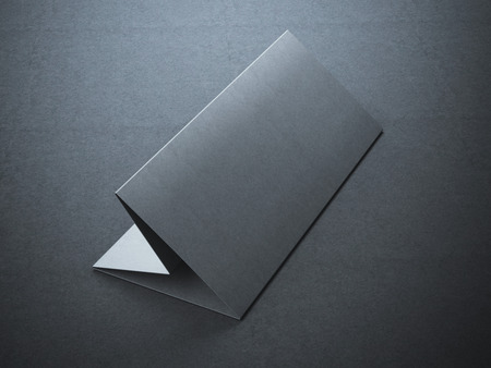 Blank black leaflet in dark studio on concrete floor