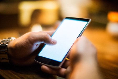 Men's hands with modern smartphone in the cafe