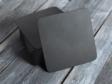 Stack of black square beer coasters on wooden table. 3d renderingの写真素材
