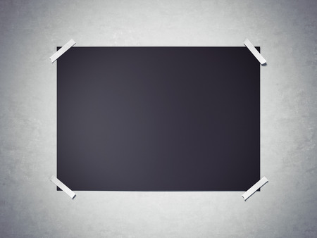 Black horisontal paper sheet attached by  tape to the gray wall. 3d renderingの写真素材