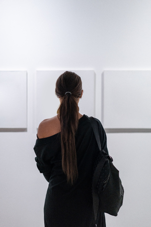 Close up of woman looking at blank canvas posters on the wall in art gallery.の写真素材