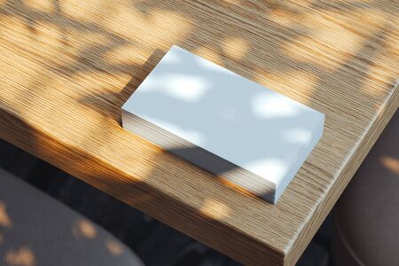 Close up of white blank illuminated by daylight business cards set on wooden table, 3d rendering.の写真素材