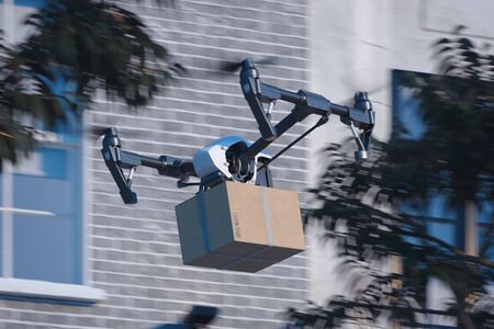 drone quadcopter delivering package to buyer flying at the street. Modern service and delivery. 3d rendering . Cityscapeの写真素材