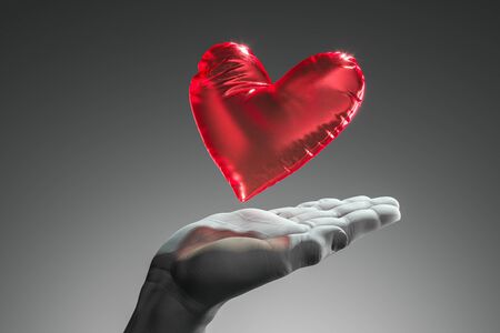 Realistic white human hand holding red heart balloon isolated on dark background. 3d rendering. Proposal. Surpriseの写真素材
