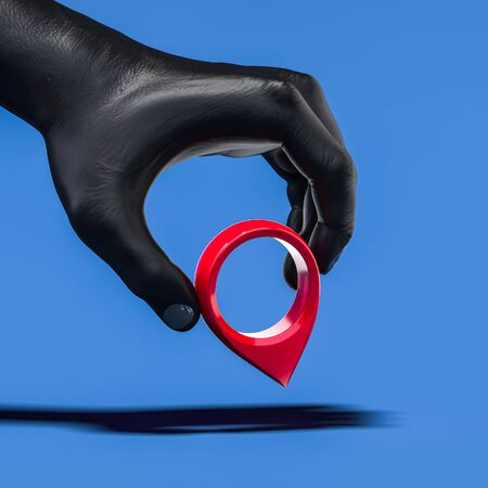 Realistic black human hand holding red map pin geotag isolated on blue background. 3d renderingの写真素材