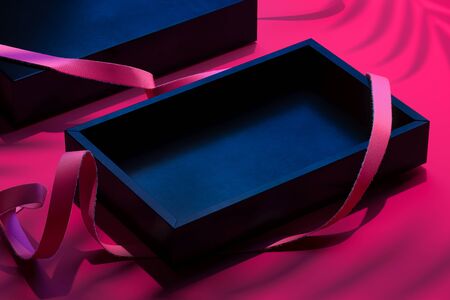 Black Blank Cardboard Box With Pink Ribbon on Pink Background With Palm Leaf Shadows. 3d rendering.の写真素材