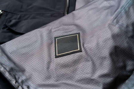 Blank Black Square Clothing Label Mockup Template on Stylish Black Sportswear. Tag Label With Copy Space, Empty Space.の写真素材