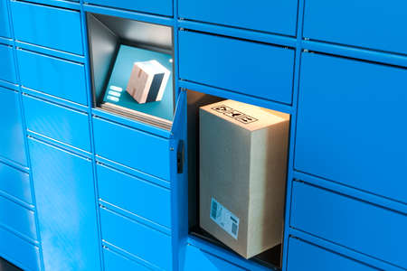 Close up Of Light Blue Self-Service Post Terminal Machine With Touchscreen Monitor and One Open Locker With Parcel Inside. Parcel In Cardboard Package. 3d rendering.の写真素材