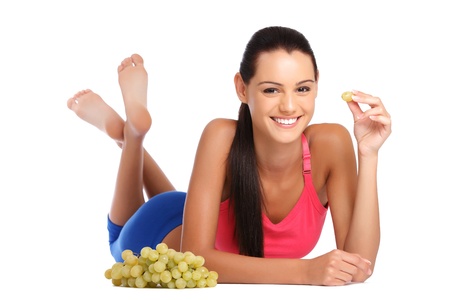 beautiful young brunette teenager posing with grape on white backgroundの写真素材