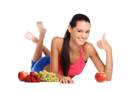 young brunette teenager posing with apples, strawberries, grapes on white backgroundの写真素材